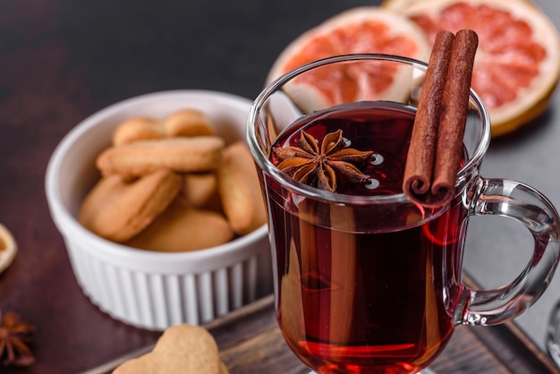 Christmas mulled red wine with spices and fruits on a dark table.