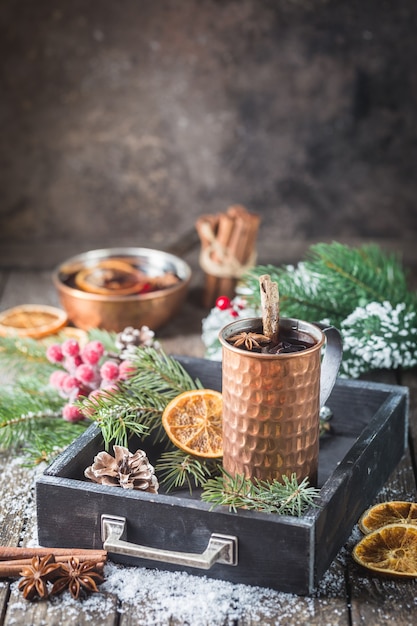 Christmas mulled red wine with spices and fruits on a wooden rustic table. Traditional hot drink at Christmas time