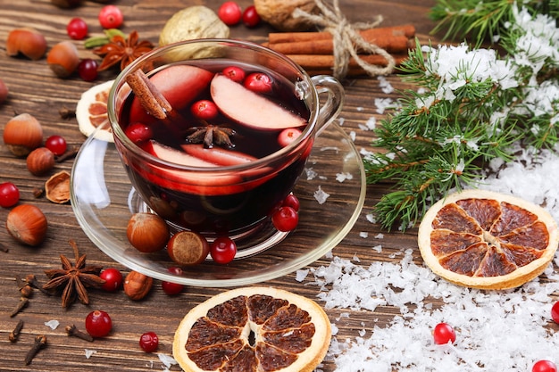 Christmas mulled wine with apple, cranberry, orange and spices on a wooden table