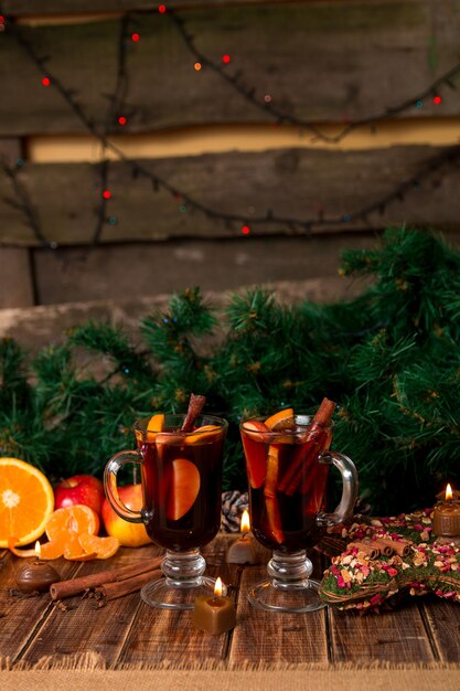 Photo christmas mulled wine with fruits and spices on wooden table. xmas decorations in background.