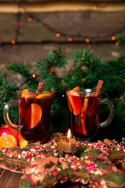 Christmas mulled wine with fruits and spices on wooden table.