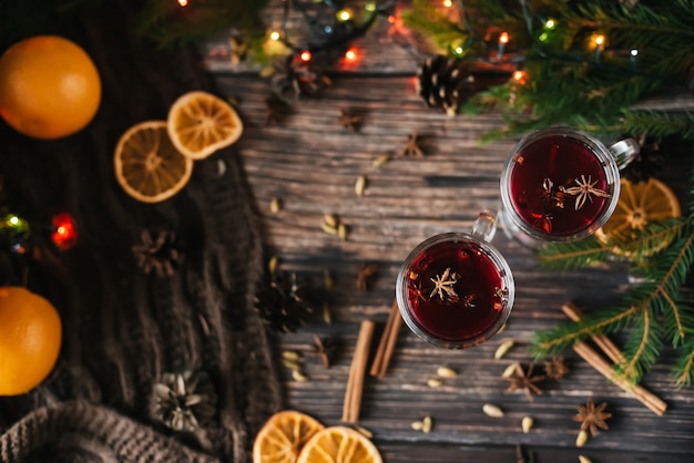 Christmas mulled wine with orange slices, cinnamon and other spices on a wooden table with a Christmas tree