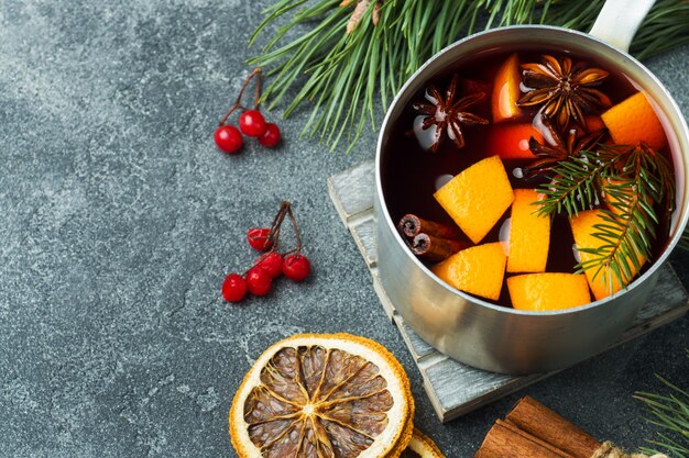 Natale vin brulè con spezie e frutta sul tavolo.