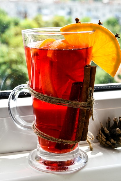 Christmas mulled wine with spices and orange on windowsill. Selective focus. Anise stars and cinnamon sticks. Christmas cones. Copy space for text