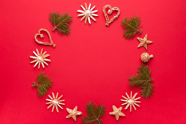 Christmas natural wood decorations and pine tree frame on red background, copy space. Flat lay, christmas card with ornaments from ecological materials, top view