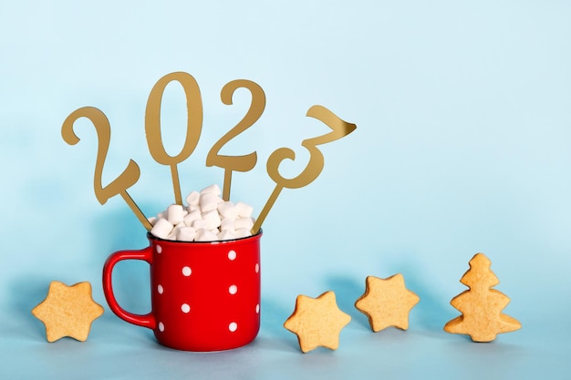 Christmas or New Year 2023 creative concept Hot chocolate in red mug and golden numbers 2023 copy space