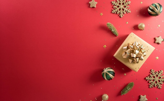 Natale e capodanno concetto di sfondo. vista dall'alto della decorazione natalizia realizzata con scatola regalo, fiocco di neve, palla di natale e rami di pino su sfondo rosso.