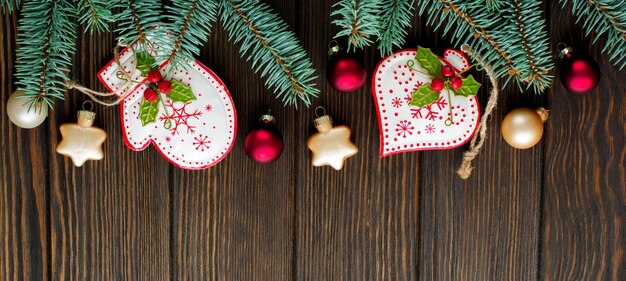 Christmas or New Year background. Fir-tree branches, different tree toys with Christmas ornament on dark brown wooden background. Selective focus. Top view. Copy space