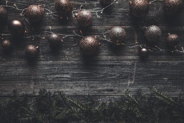 Christmas or New Year background. Vintage Christmas tree toy decoration balls and light garland over rustic wooden background, selective focus, copy space