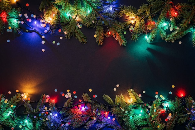 Photo christmas and new year background with copy space for text. fairy lights and decor of fir branches and confetti. flat lay, top view