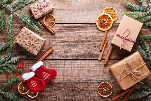 Foto sfondo di natale o capodanno con rami di abete, palle di natale, confezione regalo, fiocchi di neve in legno e stelle su fondo di legno scuro. posto per il tuo testo