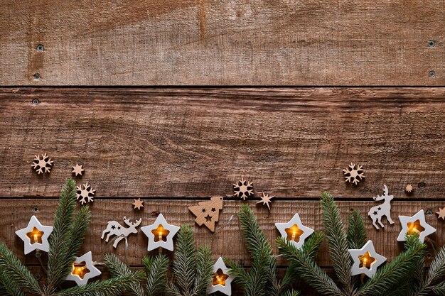 Christmas or New Year background with fir branches, garland, Christmas balls, gift box, wooden snowflakes and stars on dark wooden background. Place for your text