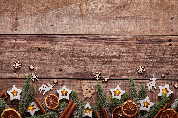 Christmas or New Year background with fir branches, garland, Christmas balls, gift box, wooden snowflakes and stars on dark wooden background. Place for your text