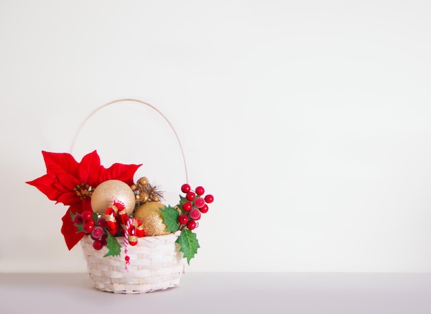 Christmas New Year basket with toy balls fir tree branch poinsettia and berries for decoration