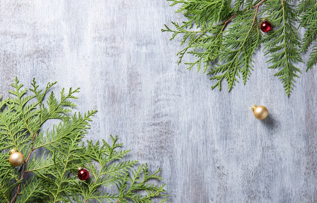 Christmas and new year border design on the light wood background with thuja tree, and christmas balls. top view and copy space