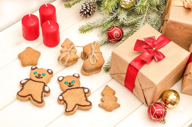 Christmas and New Year card with a composition of gifts, Christmas tree decorations and gingerbread cookies on a white wooden background