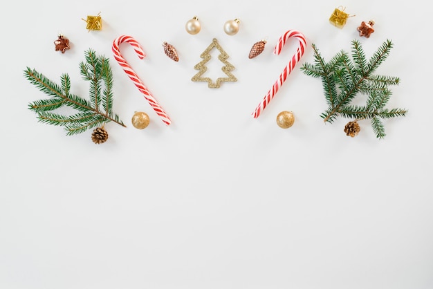 Christmas and new year composition. Christmas gift, knitted blanket, cones, fir branches, candy cane on white wooden background. 