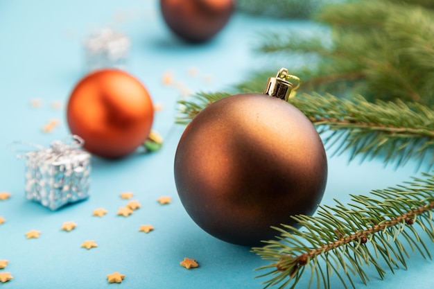 크리스마스 또는 새해 구성입니다. 파란색 종이 배경에 장식, 청동 공, 전나무 및 가문비나무 가지. 측면 보기, 닫기, 선택적 초점입니다.
