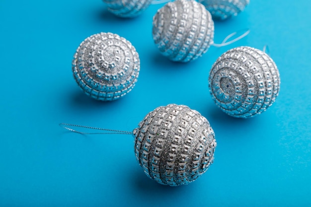 Christmas or New Year composition. Decorations, silver balls, on a blue paper background. Side view, close up.