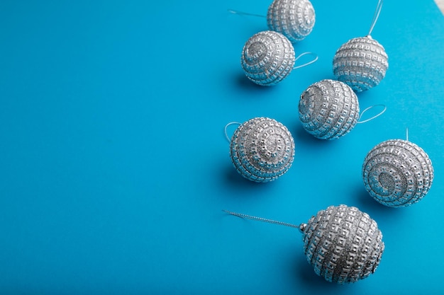 Christmas or New Year composition. Decorations, silver balls, on a blue paper background. Side view, copy space.