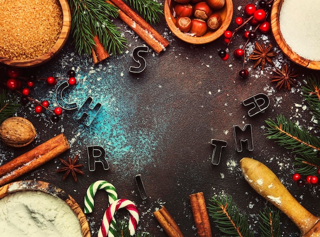 ベーキング用の材料または金色の雪片を使用したクリスマスまたは新年の構成クリスマスボール緑のモミの枝青茶色の背景フレームの松ぼっくりトップビュー