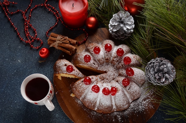 Christmas and New Year concept Delicious lemon cake with red sweet cherries and sugar powder