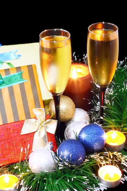 Christmas and New Year decoration- balls, tinsel, candel and glasses of champagne .On black background.