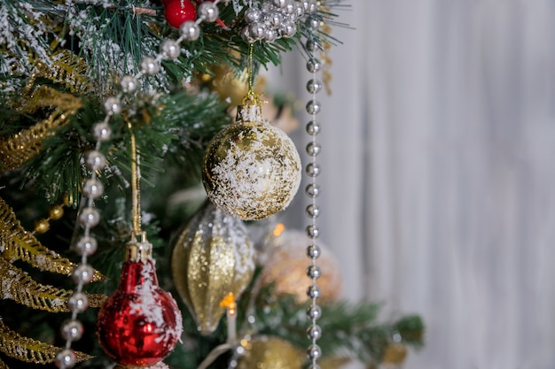 Рождественские и новогодние украшения. Зимние каникулы арт дизайн с праздничными шарами. Красивый крупный план рождественской елки украшенный с звездой золота, ягодой падуба, сусалью.