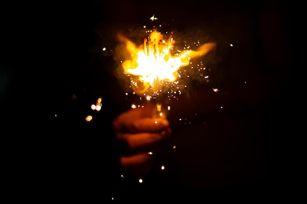 Christmas and new year eve concept image with close up of a pair of man hands taking a red fire spar