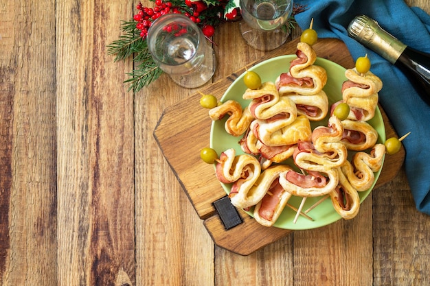 Christmas and New Year food Holiday snack puff dough Christmas tree with olive and bacon Top view