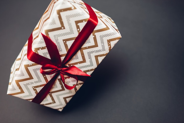 Christmas and New year gift box wrapped in festive paper and decorated with red ribbon