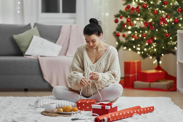 Confezione regalo di natale e capodanno da parte di una donna a casa durante le vacanze invernali