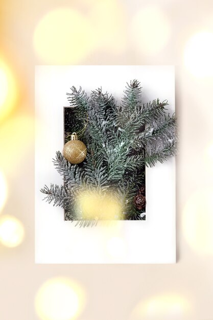 백서 프레임에 황금 크리스마스 공과 전나무 나무 가지와 크리스마스 또는 새 해 인사말 카드. 황금 bokeh 빛입니다. 베이지색 배경입니다. 평면 위치, 복사 공간