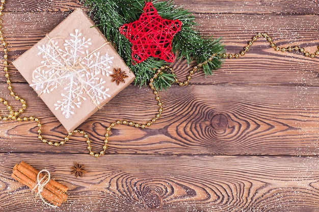 Christmas and New Year holiday background. Decor with gifts, fir branches, cones, star, beads, snowflakes, cinnamon sticks on a wooden table. Flat lay, empty space