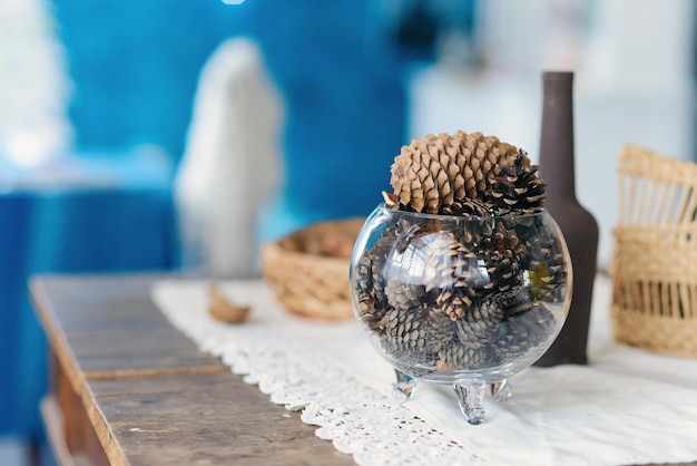 Christmas and new year home decoration close up of glass ball vase with cones inside on blue