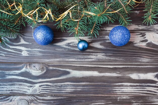 Christmas and New Year layout on a wooden background. Postcard with a fir branch and toys. View from above. Flat lay. Copy space