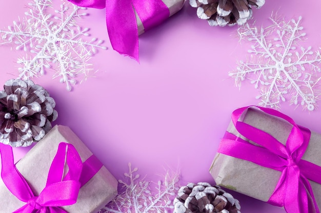 Christmas and New Year mockup on pink background. Frame made of snowflakes, cones and gift boxes. View from above. Flat lay. Copy space