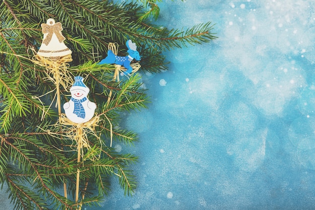 Sfondo blu di natale e capodanno con rami di abete e giocattoli di legno di natale. vista dall'alto