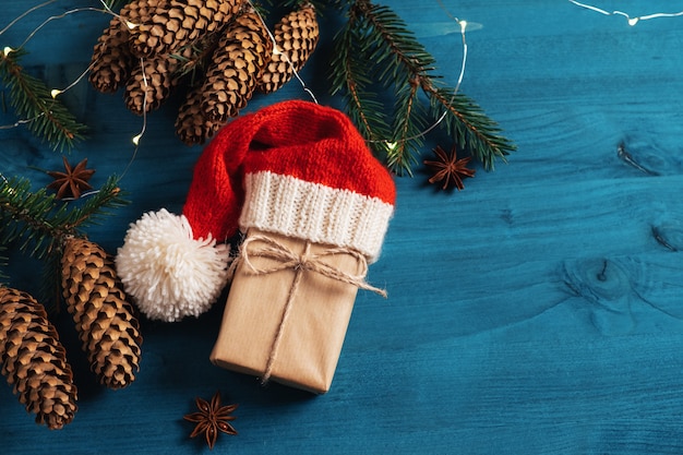 Рождественский или новогодний подарок в вязаной шапке Деда Мороза, упакованной в крафт-бумагу и перевязанной бечевкой.