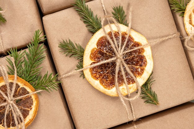 Christmas or New Year's pattern from boxes in craft paper with dried oranges, spruce branches and twine close-up.