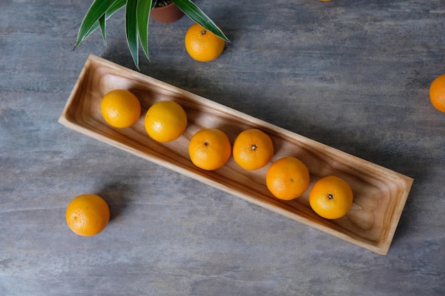 Christmas or New Year's still life of tangerines lying on wooden rectangular plate with spruce branches