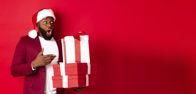 Christmas new year and shopping concept surprised black man looking at xmas presents with person