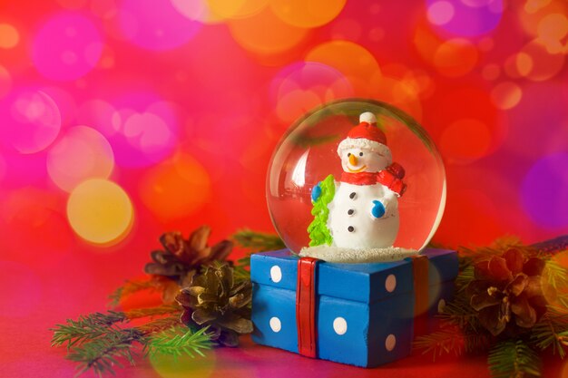 Christmas and new year snow globe snowman inside on red bokeh background 