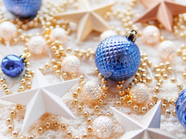 Photo christmas and new year star decorations on white knitted . metal light bulbs with delicate pattern, golden beads and blue balls.