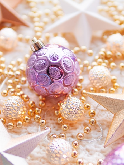 Photo christmas and new year star decorations on white knitted . metal light bulbs with delicate pattern, golden beads and violet balls.