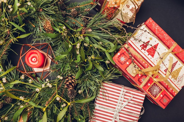 Рождественский и новогодний венок из веток ели, сосны, омелы, шишек с горящей свечой внутри и подарочных коробок. Эко и натуральное украшение для дома