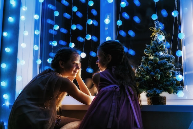 Foto la notte di natale le sorelle si guardano alla finestra aspettando babbo natale