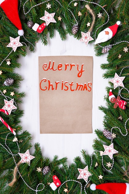 Christmas note and fir branches with toys on a white background.
