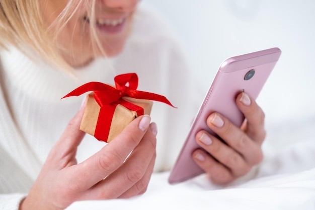 크리스마스 온라인 쇼핑 여성 구매자는 휴대 전화로 주문합니다. 여성 구매 선물은 손에 크리스마스 선물 상자를 준비합니다. 겨울 방학 판매