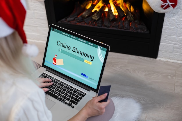 Christmas online shopping. Female buyer with laptop, copy space on screen. Woman buys presents, prepare to xmas eve, sitting among gifts boxes and packages. Winter holidays sales